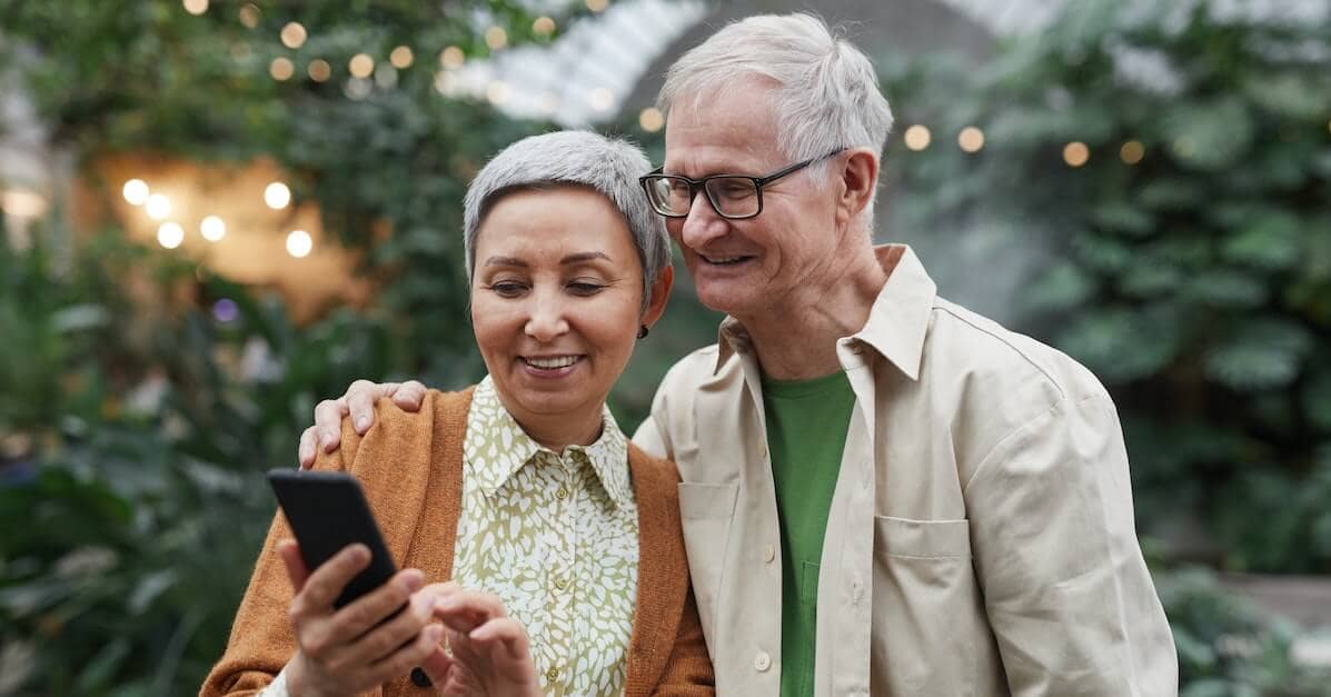 An older couple looks at their smartphone outside