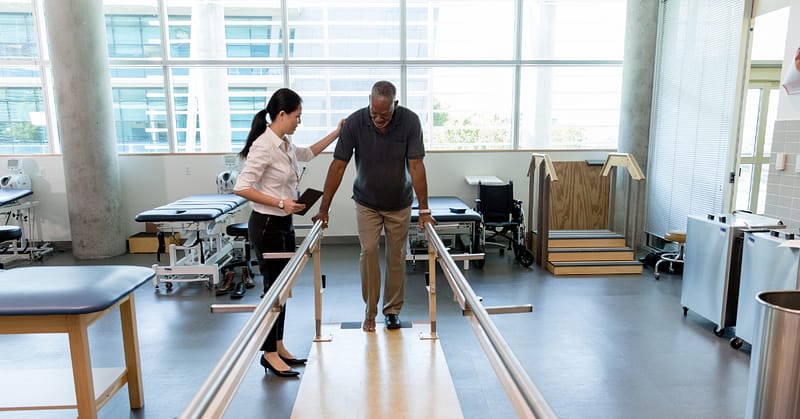 Physical therapist helping patient with walking exercise